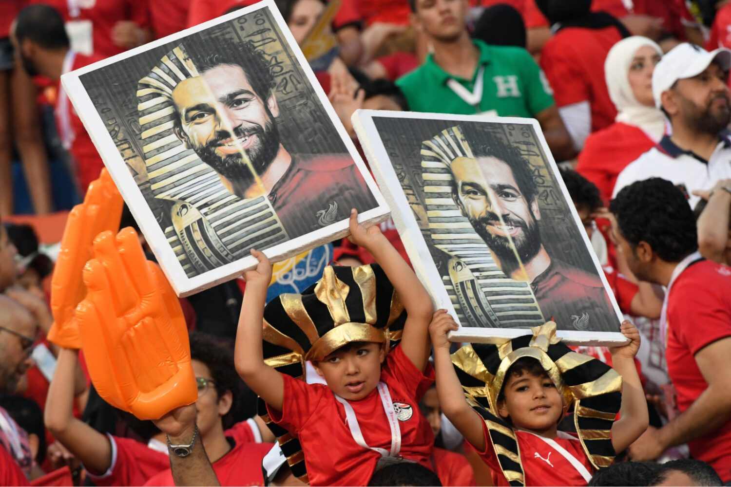 Fans holding pharaoh-themed soccer posters at stadium